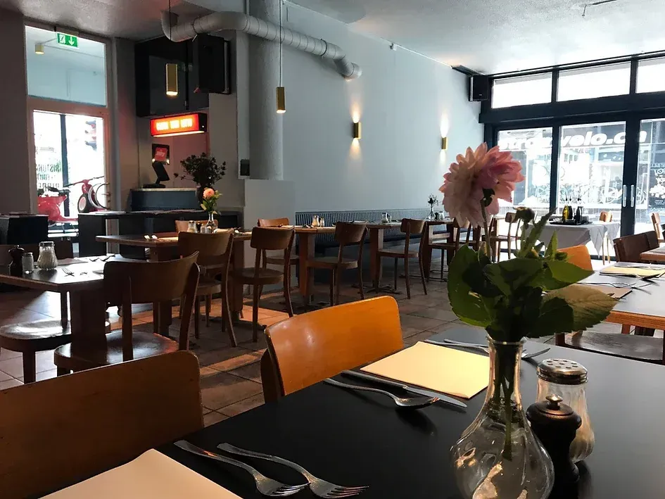 Ein Restaurant mit Tischen und Stühlen und einer Vase mit Blumen auf dem Tisch.