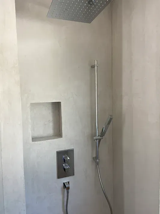 Eine Dusche mit Duschkopf und Schlauch in einem Badezimmer.