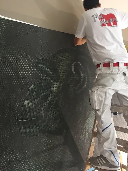 Ein Mann steht auf einer Leiter und malt ein Bild an eine Wand.