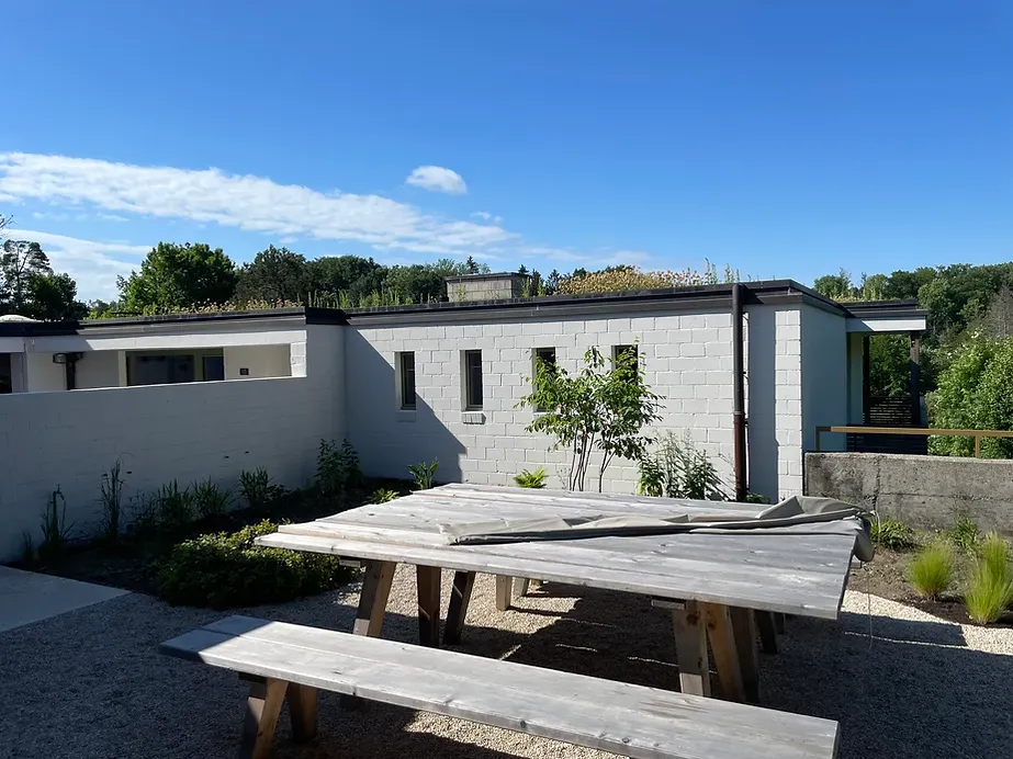 Ein hölzerner Picknicktisch mit Bänken vor einem weißen Gebäude