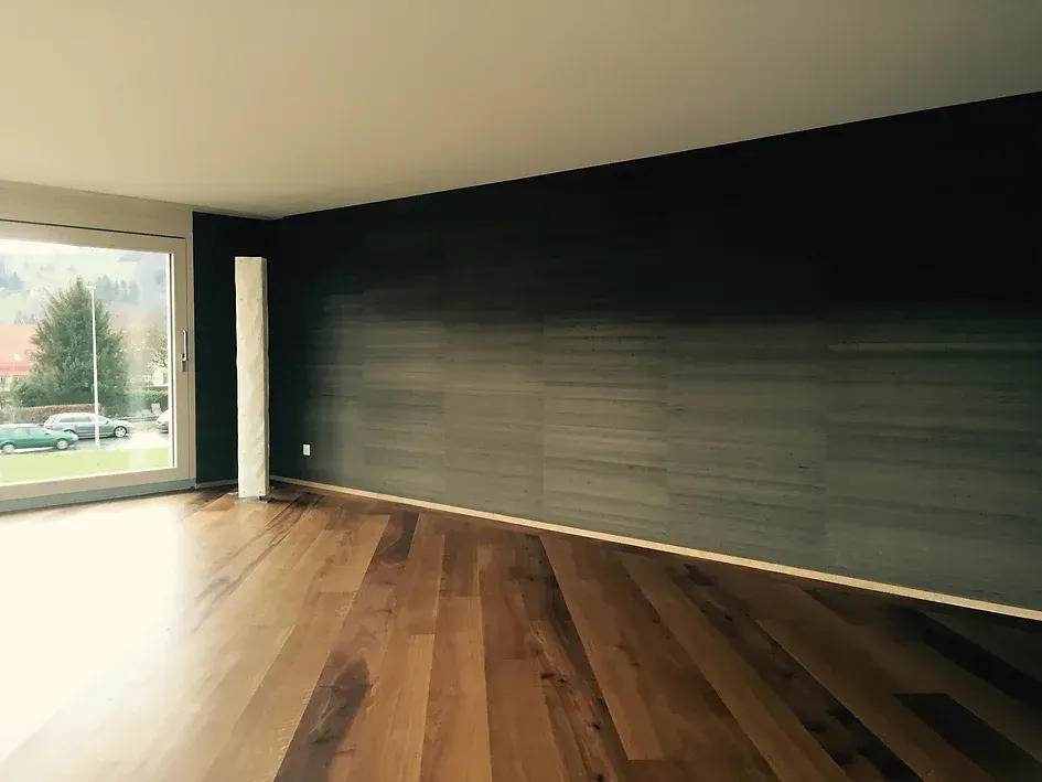 Ein leeres Wohnzimmer mit Hartholzböden und einem großen Fenster.