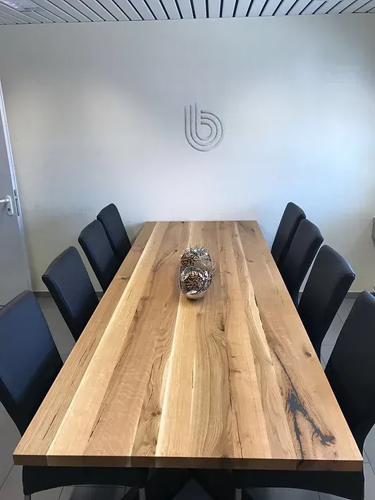 Ein langer Holztisch mit schwarzen Stühlen in einem Konferenzraum