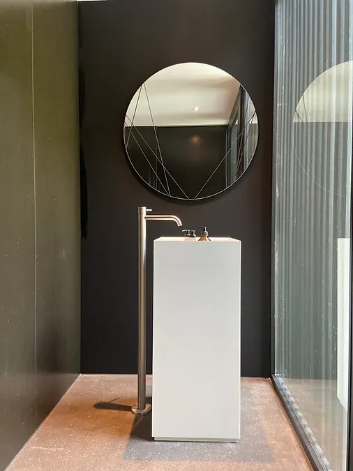 Ein Badezimmer mit einem weißen Waschbecken und einem runden Spiegel