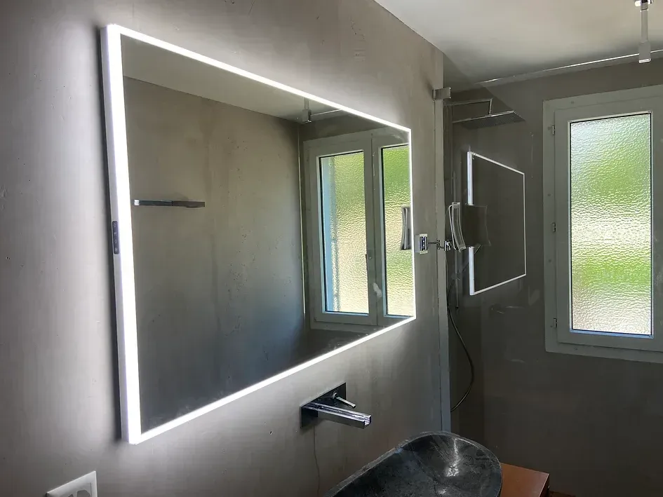 Ein Badezimmer mit großem Spiegel und Waschbecken.