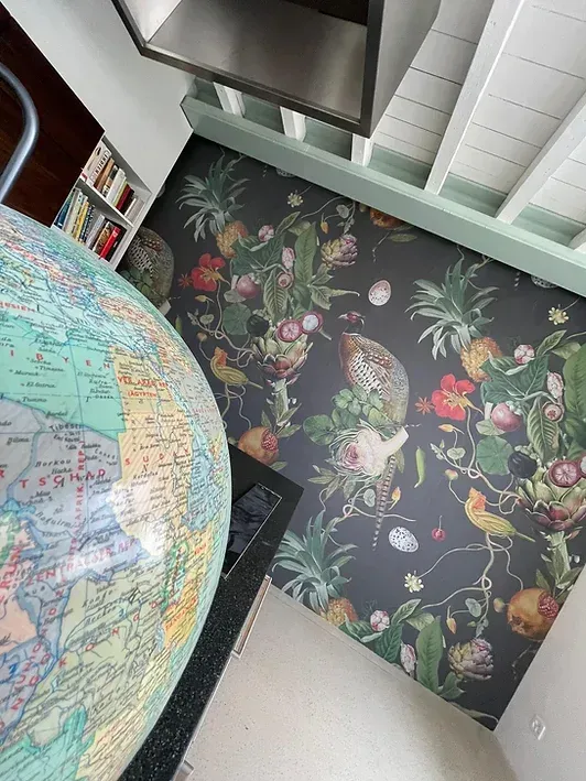 Auf dem Boden steht neben einer Blumentapete ein Globus.