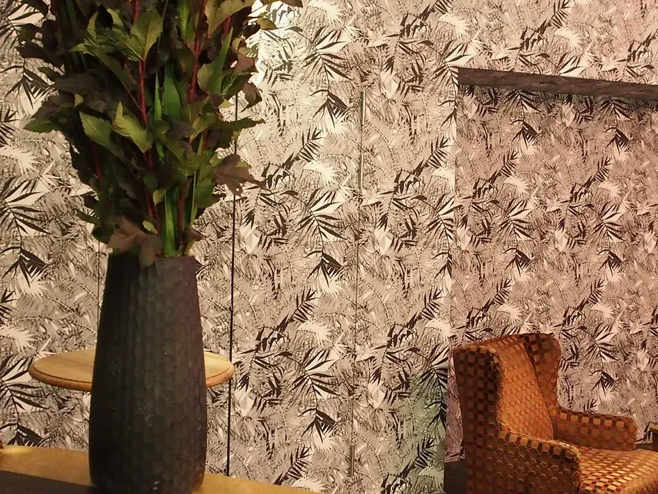 Auf einem Tisch vor einem Stuhl steht eine Vase mit Pflanzen.