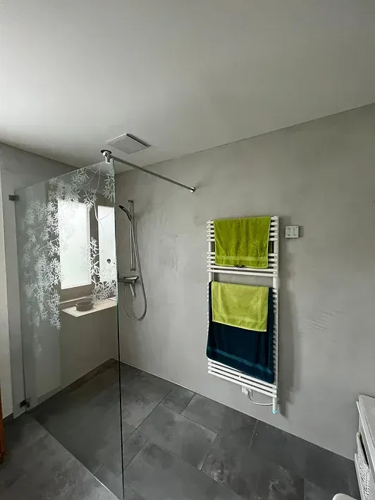 Ein Badezimmer mit ebenerdiger Dusche und Handtuchhalter.