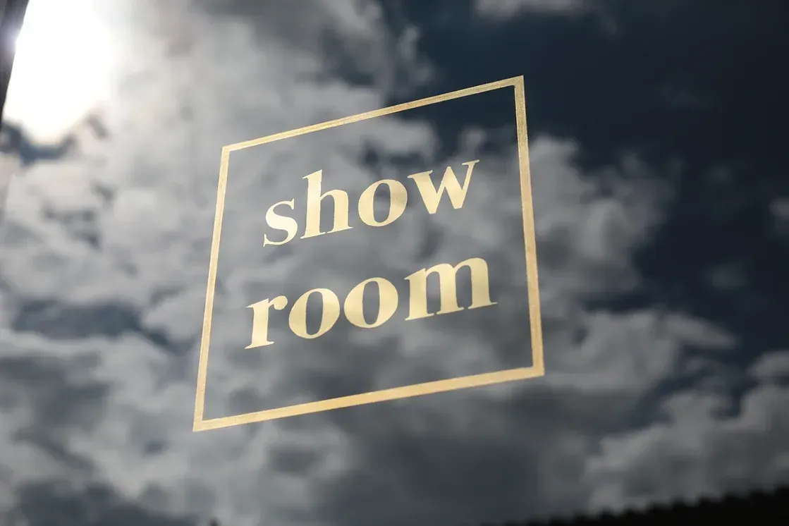Ein Schild mit der Aufschrift „Showroom“ vor einem bewölkten Himmel