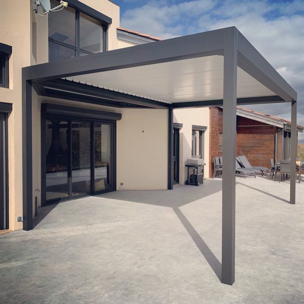 Une pergola protégeant du soleil une portion de la terrasse en béton.