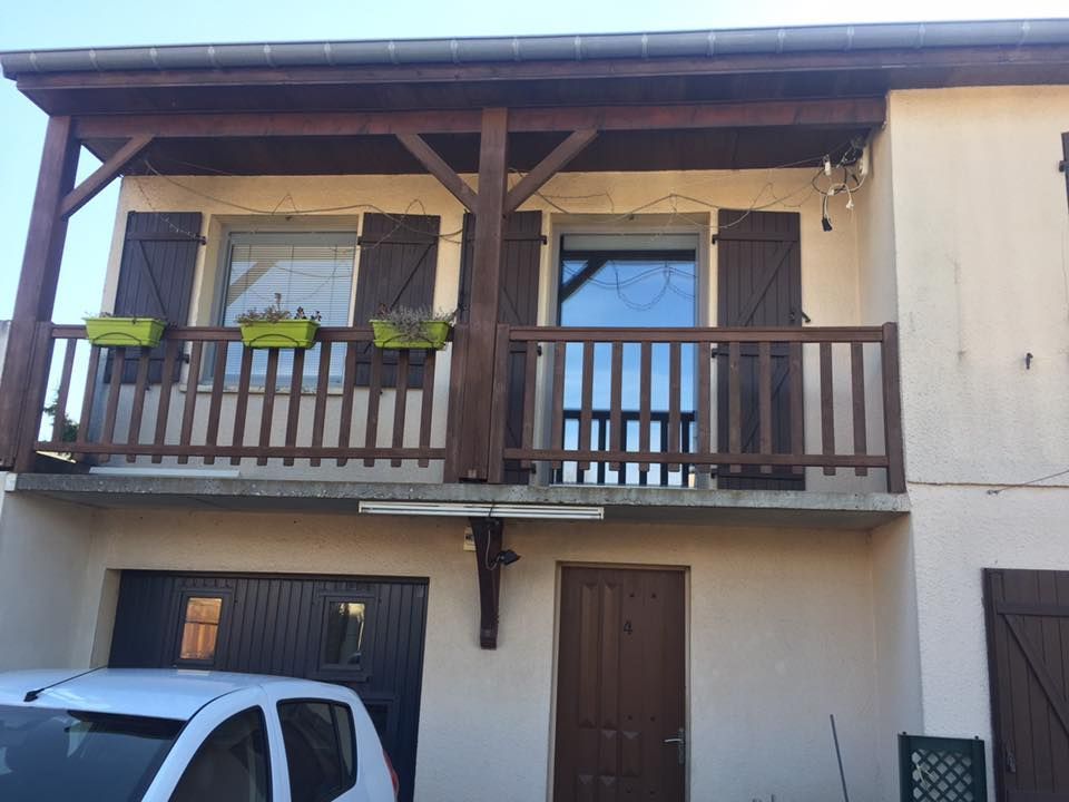 Étage avec balcon dont les volets et garde-corps sont en bois sombre.