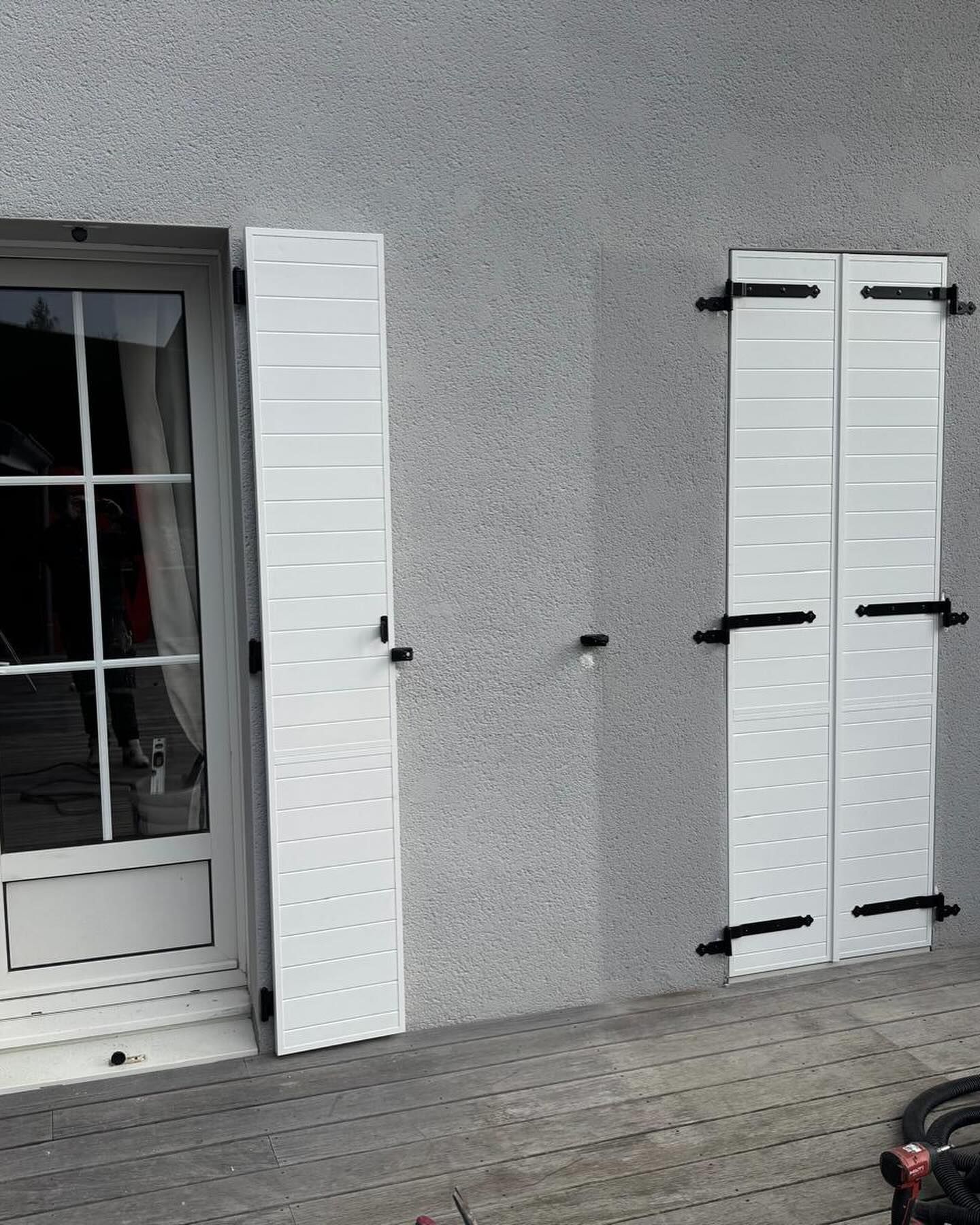 Un des volets blancs d'une fenêtre ouvert.