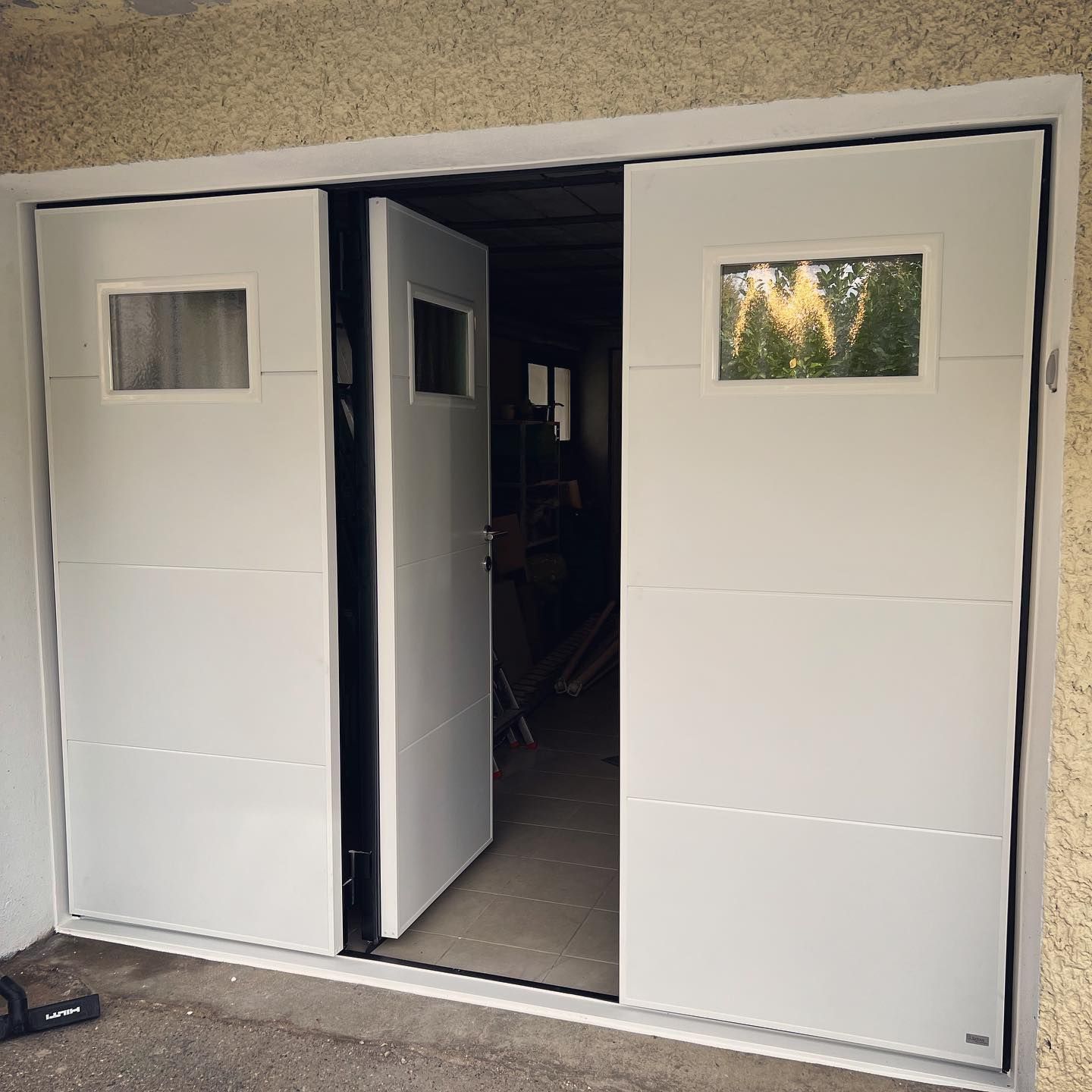 Porte de garage à trois battants dont la partie centrale est ouverte.