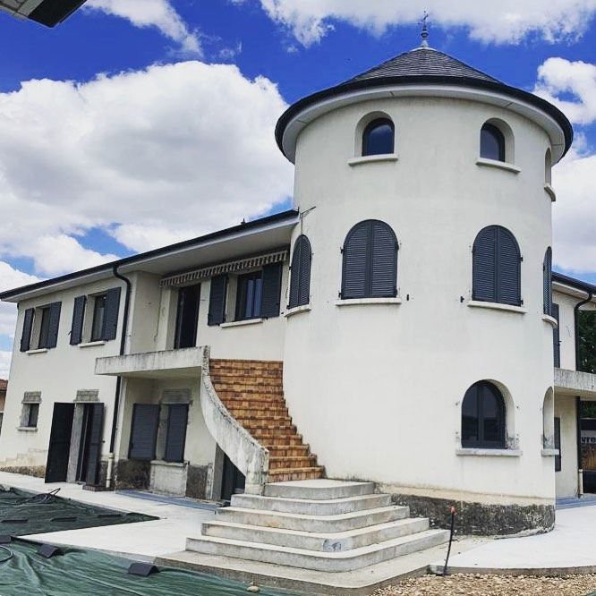Maison avec escalier extérieur menant à un étage autour d'une grande tour.