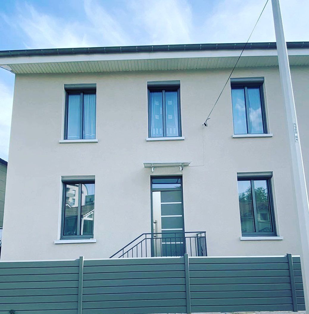 Maison sur deux niveaux avec un escalier d'accès vers la porte d'entrée.