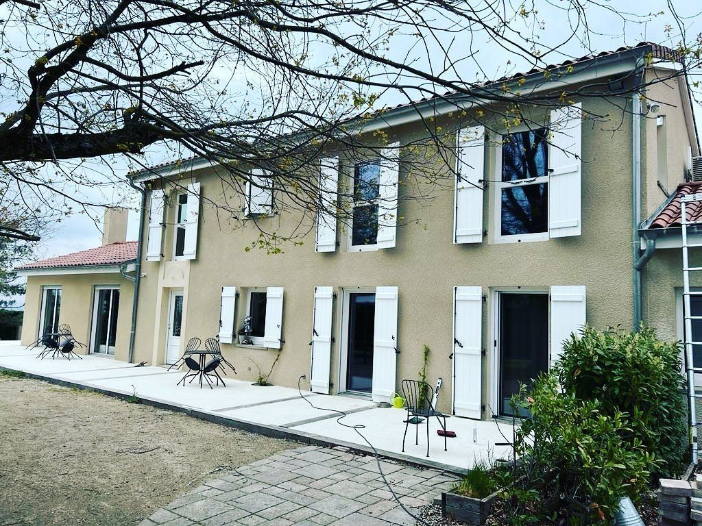 Grande habitation sur deux niveaux avec des volets blancs.