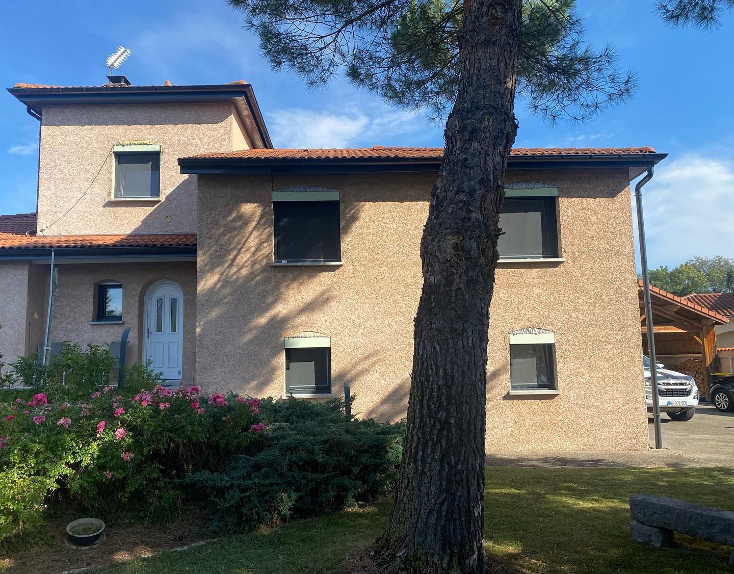 Grande maison aux murs crépis avec plusieurs fenêtres.