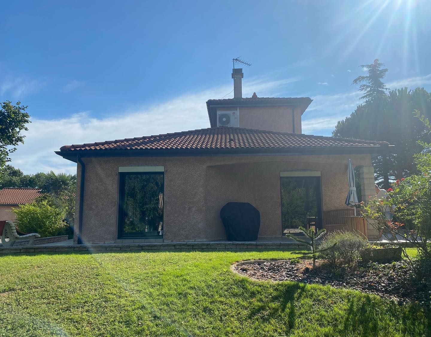 Maison aux murs crépis avec deux grandes fenêtres.