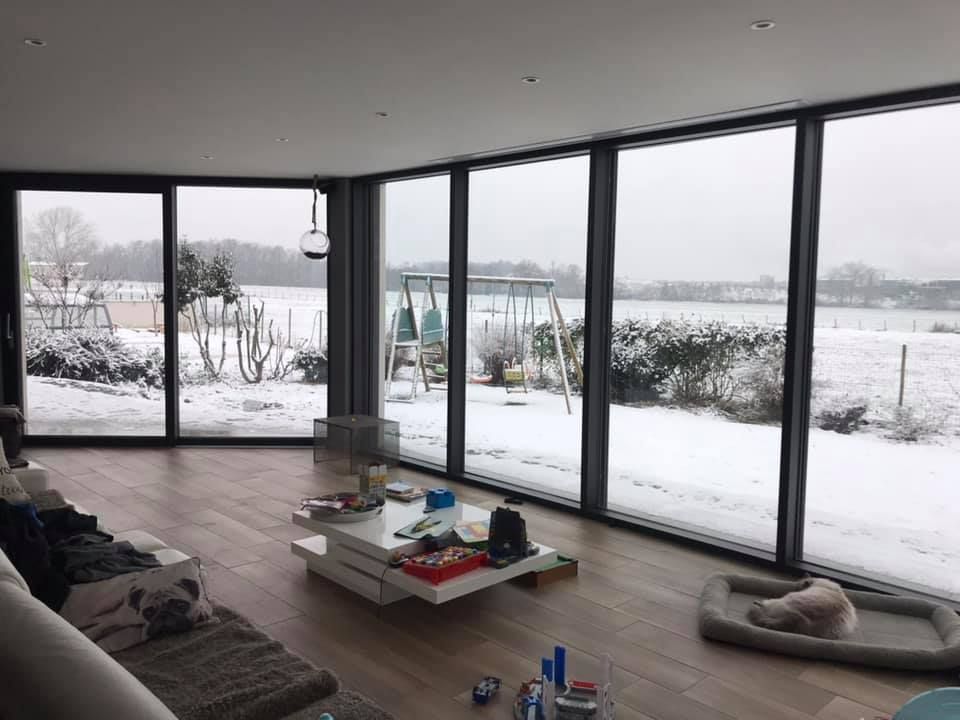 Une grande baie vitrée sur toute la pièce donnant sur un paysage enneigé.