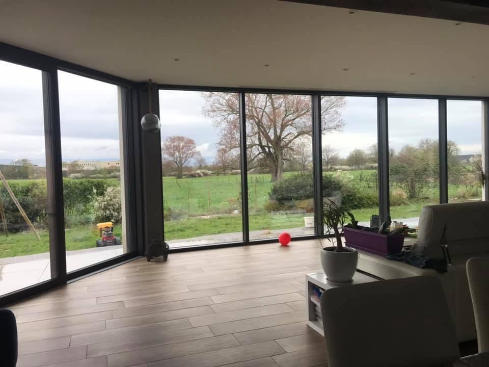 Grande baie vitrée d'un salon donnant vu sur le jardin.