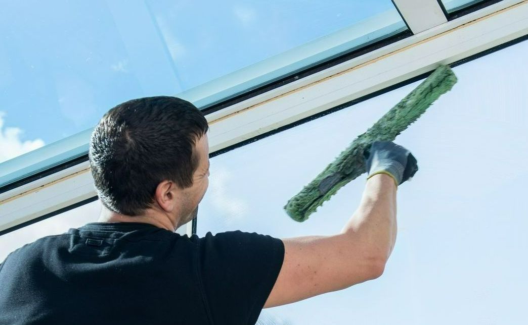 Un professionnel de dos nettoie des vitres.