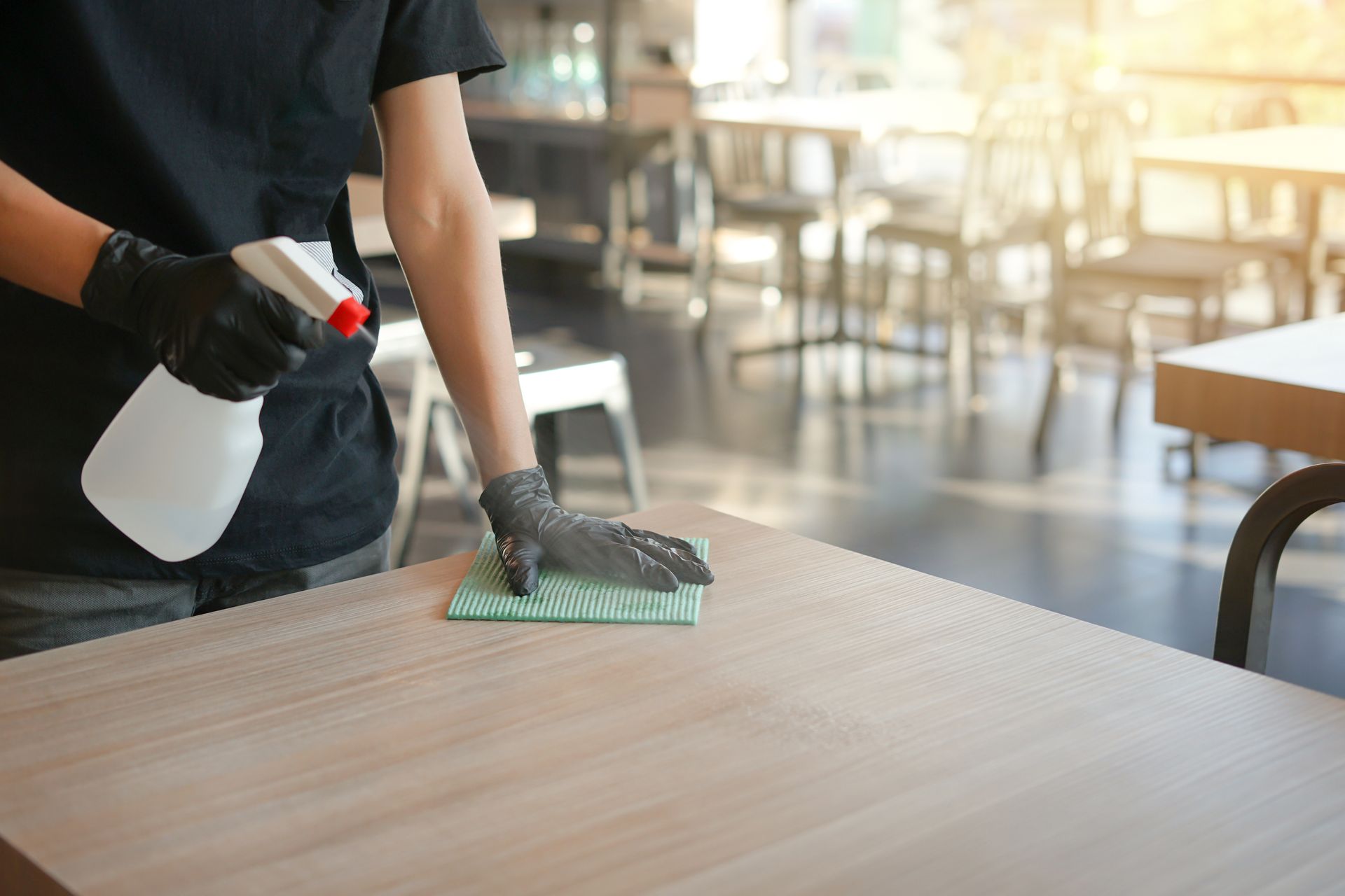 Professionnelle nettoyant une table dans un réfectoire.
