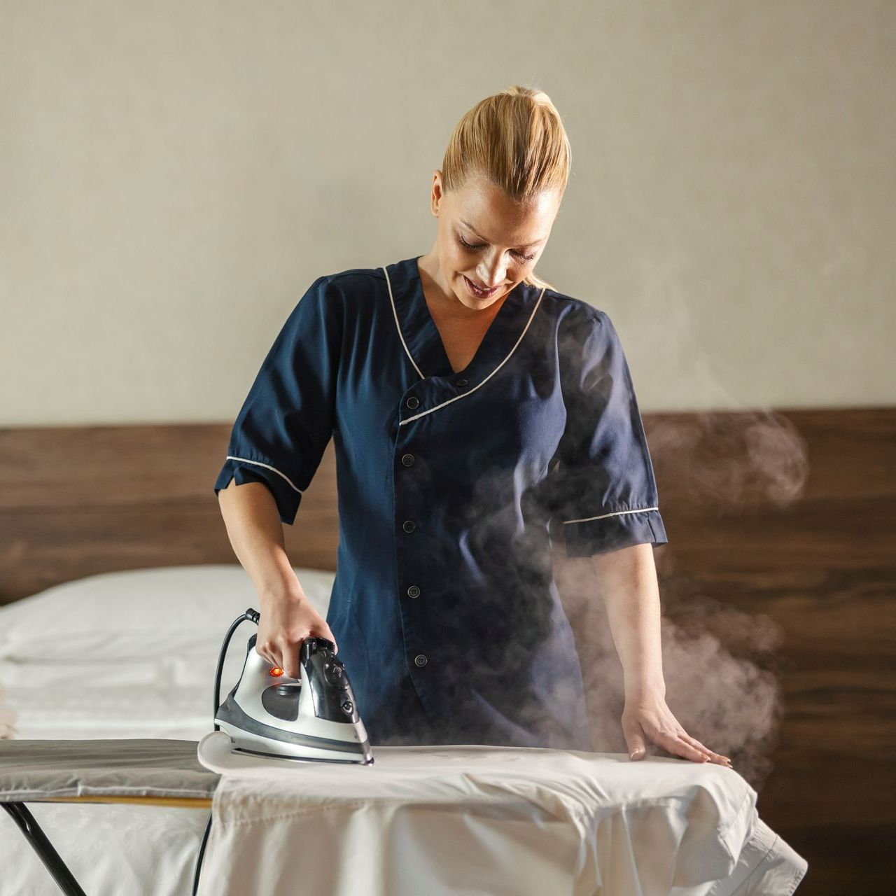 Une professionnelle repasse des draps.