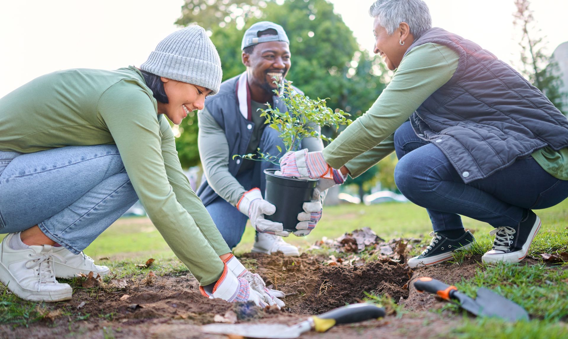 Trois personnes jardinent en souriant.
