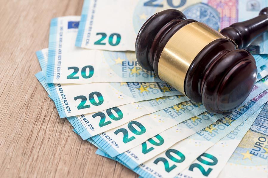 Un mazo de juez de madera reposa sobre una pila de billetes de 20 euros.