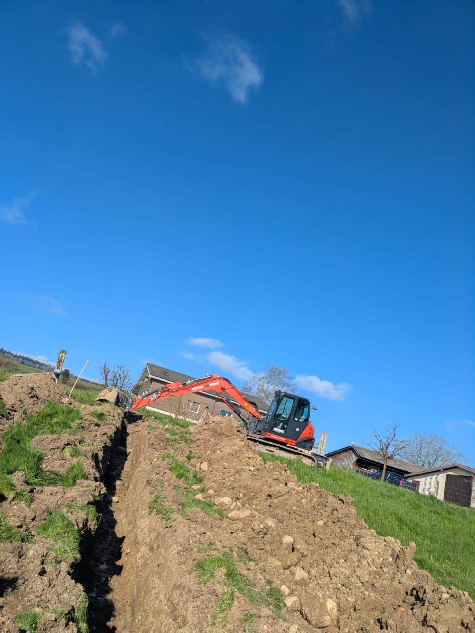 Ein Bulldozer gräbt einen Graben in ein Feld. Foto von M. Stöckli Baudienstleistungen