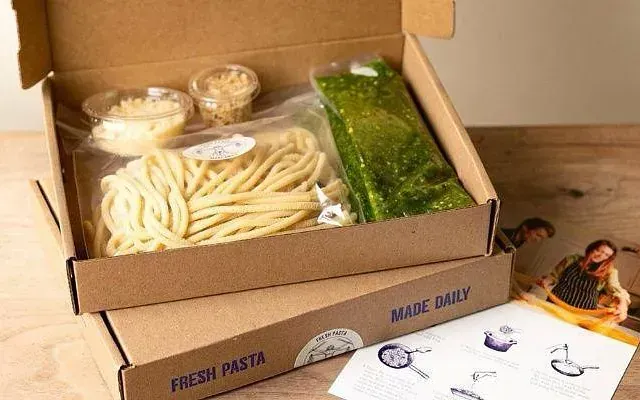 Dos cajas de pasta y salsa están sobre una mesa de madera.