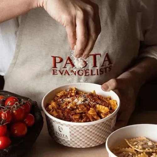 Una persona está agregando sal a un plato de pasta.