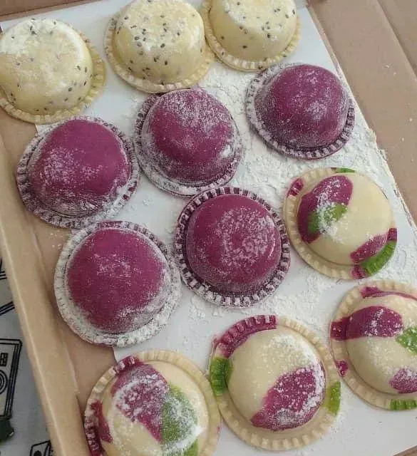 Una bandeja de pasteles morados y blancos sobre una mesa.