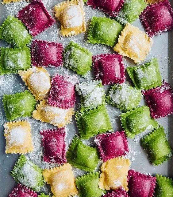 Un montón de ravioles coloridos están sobre una bandeja.