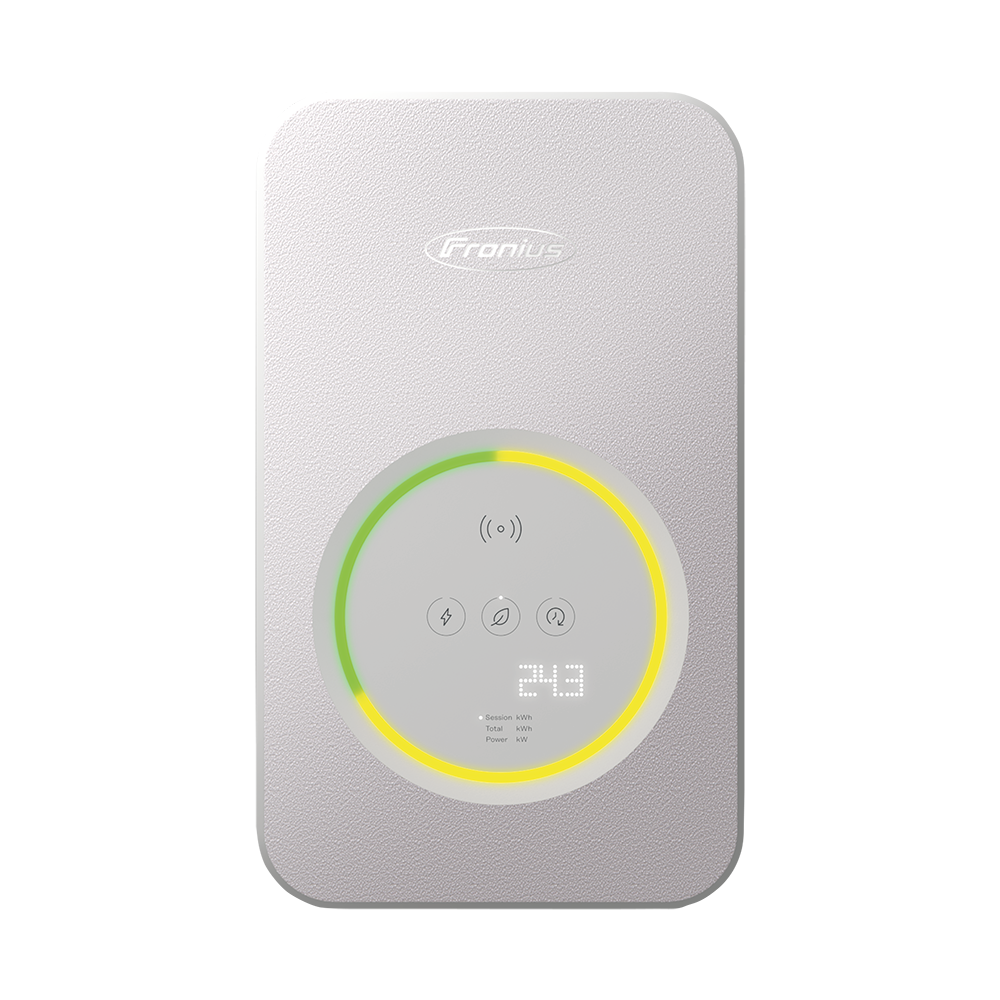 Frau lädt zu Hause ein Elektroauto auf. Ladestation mit Fronius-Logo.