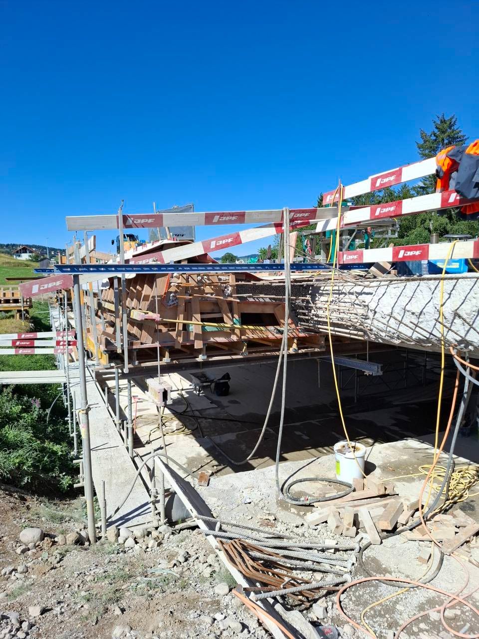 Structure en béton partiellement construite sur un chantier, avec des échafaudages et des drapeaux.