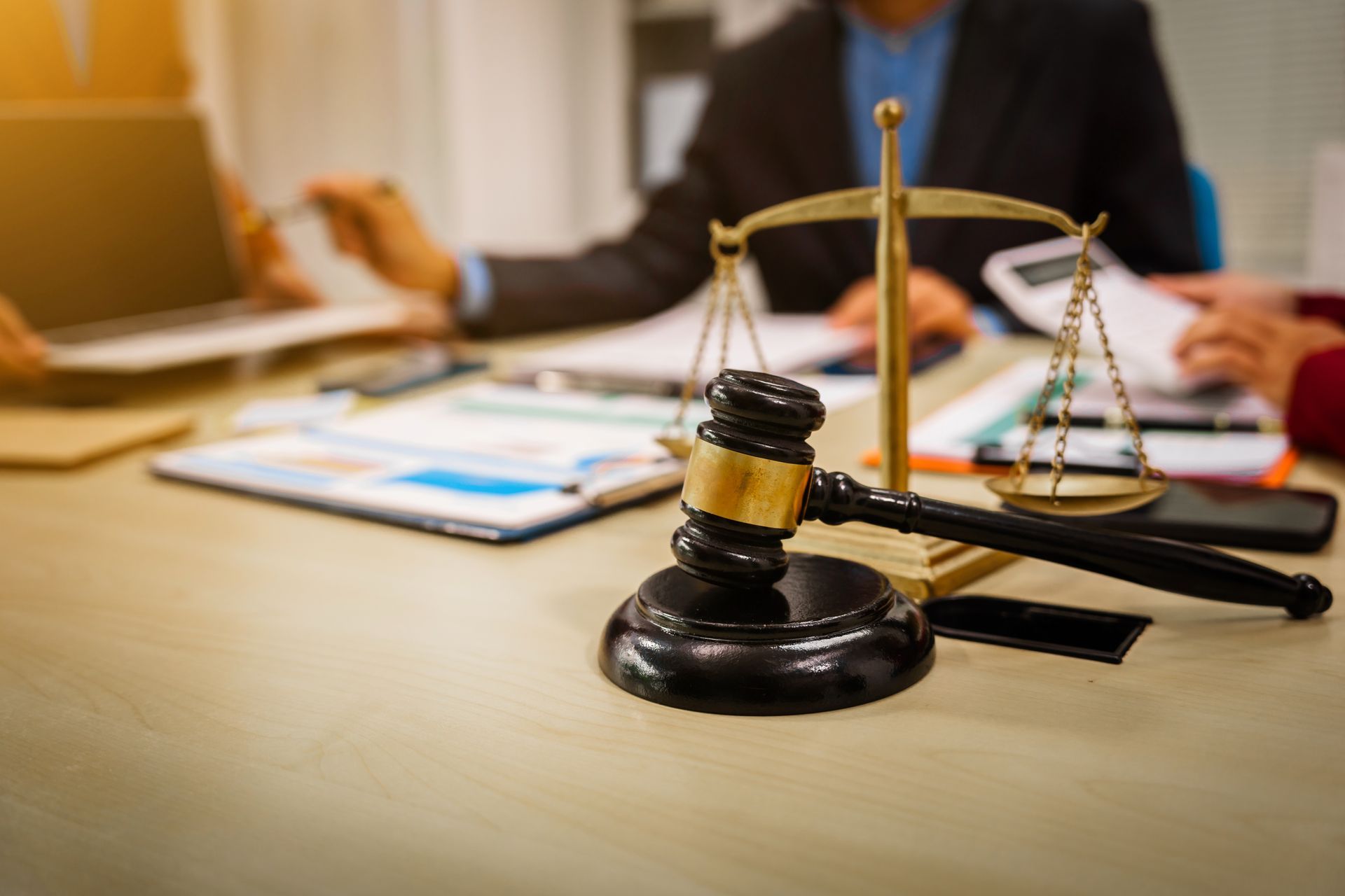 Balance et marteau dde la justice en premier plan d'un bureau couvert de documents