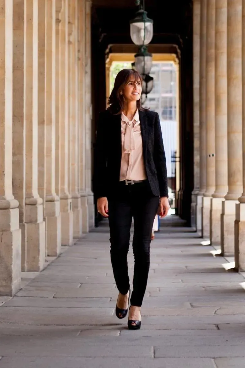 Me JOURNO, en tailleur, marche sous une colonnade