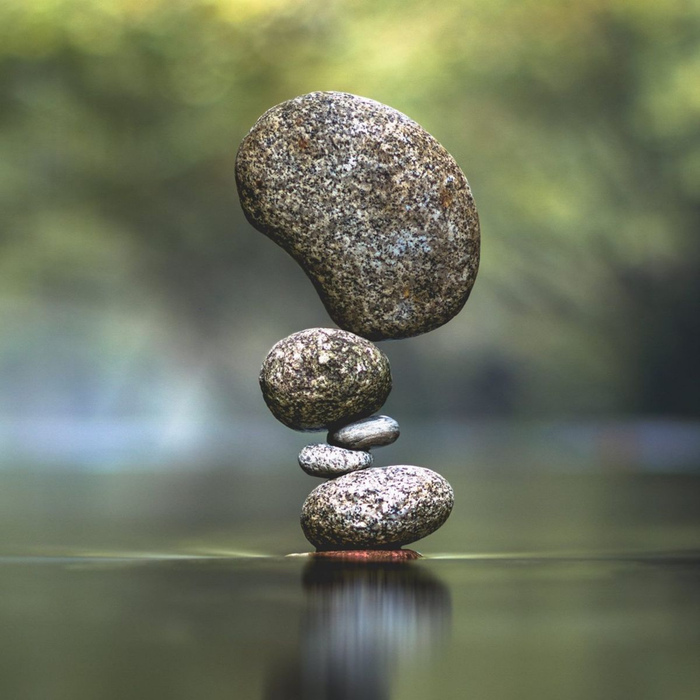 Piedras apiladas en equilibrio sobre el agua, fondo verde borroso.