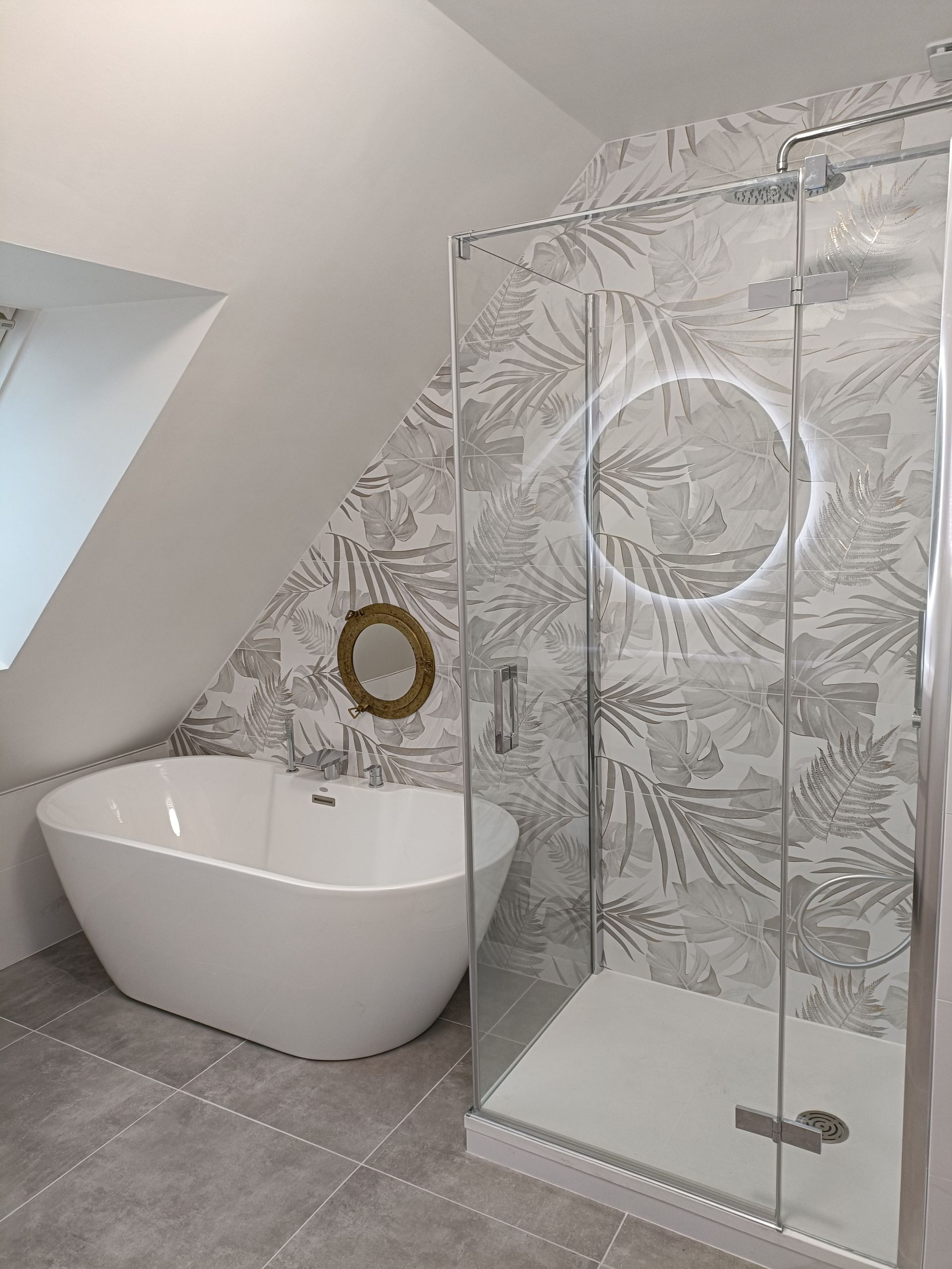 Salle de bains moderne avec baignoire îlot, douche en verre et murs carrelés.