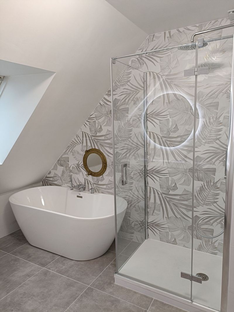 Salle de bains moderne avec baignoire îlot, douche en verre et carrelage aux murs et au sol.