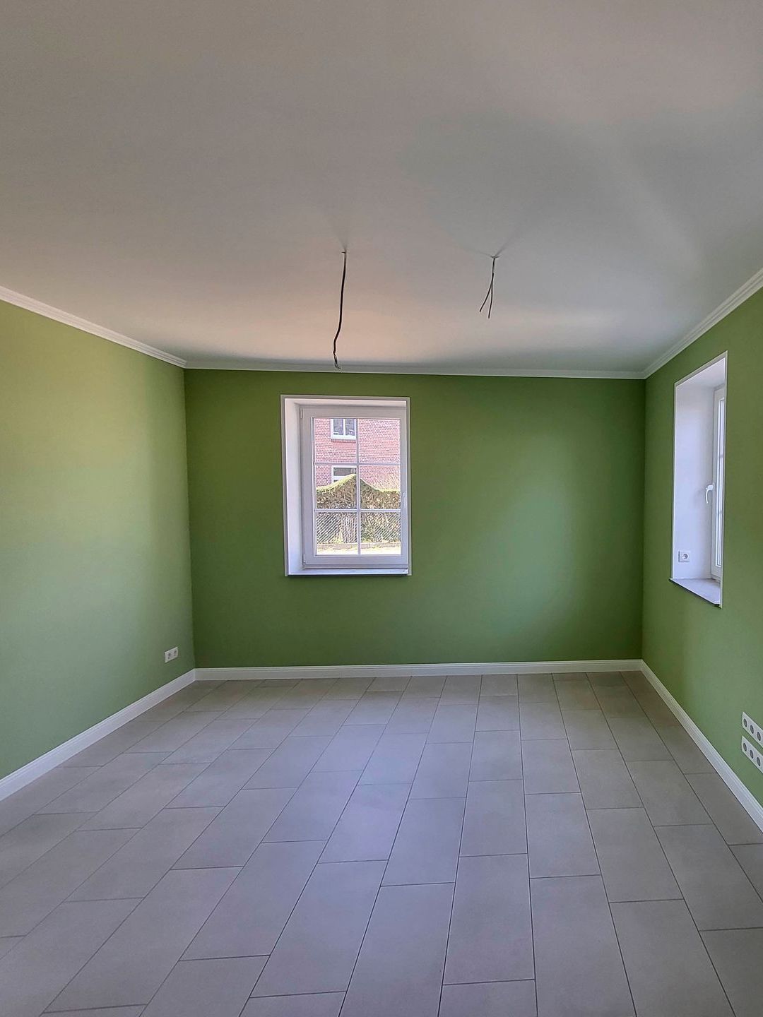 ein leerer Raum mit grünen Wänden und einem Fenster