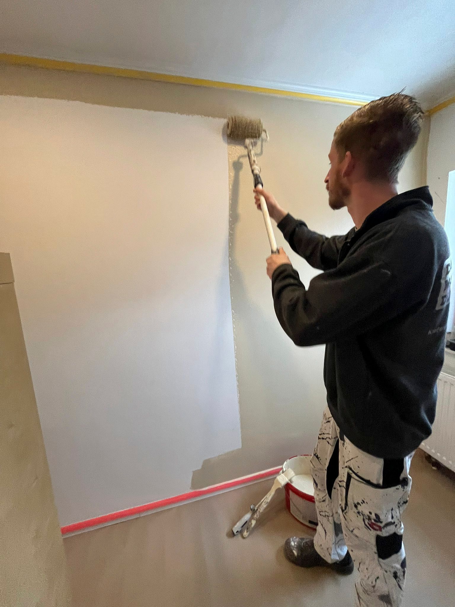 Ein Mann malt eine Wand mit einer Farbrolle