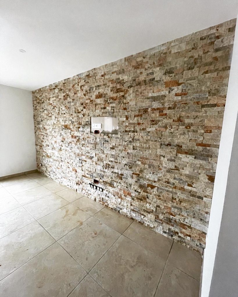 Un mur en pierres et un sol carrelé.