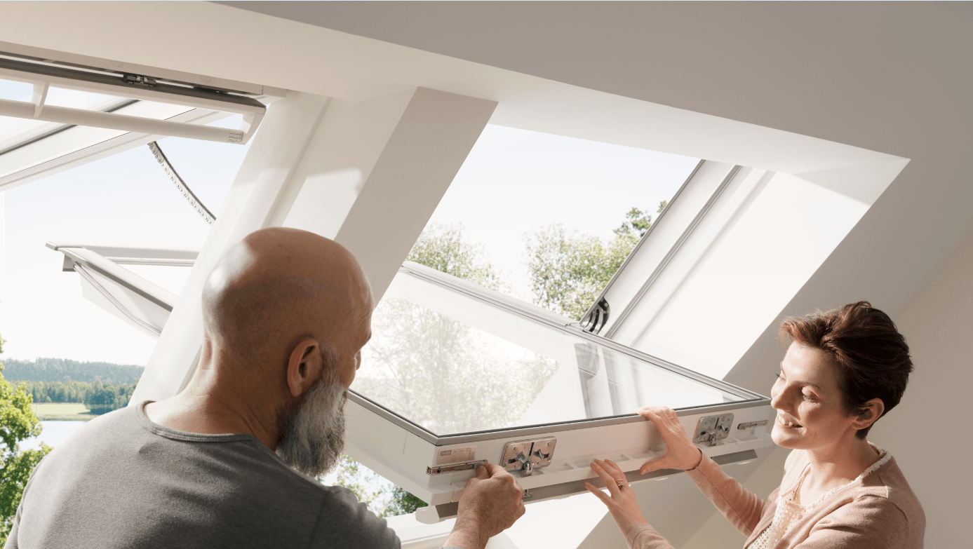 Deux personnes ouvrant une fenêtre de toit