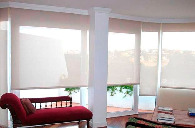 Una sala de estar con un sofá rojo y persianas blancas en las ventanas.