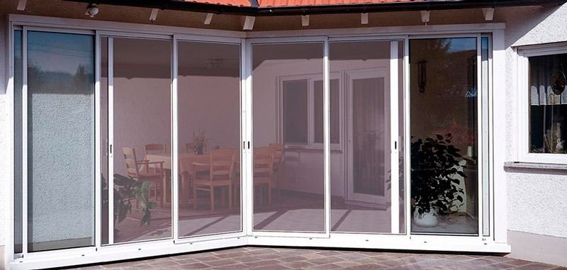 Una casa blanca con un porche cubierto y puertas corredizas de vidrio.