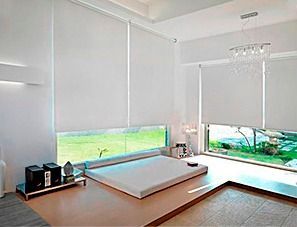 Hay una cama en el medio de la habitación con persianas blancas en las ventanas.