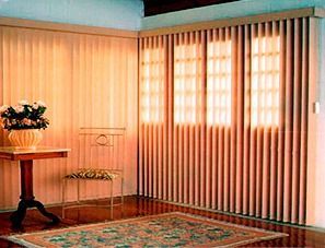 Una sala de estar con persianas verticales, una silla, una mesa y una alfombra.