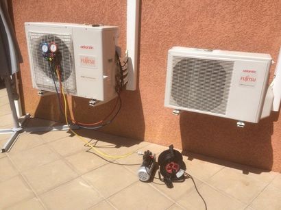 Unités de climatisation murales extérieures avec outils et câbles sur une terrasse ensoleillée.