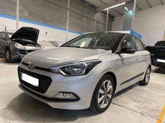 Un Hyundai i20 plateado está estacionado en un garaje con el capó levantado.